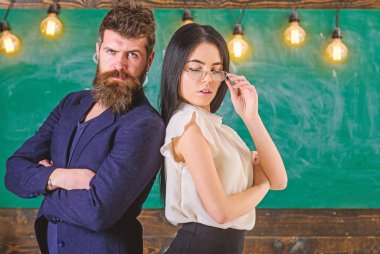 Sakal ve gözlük stand sırt sırta, kara tahta arka plan öğretmen olan adam. Ekip çalışması kavramı. Öğretmen ve öğretmen rahat görünüyor. Bayan ve birlikte okulda çalışan hipster