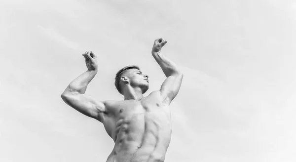 Чоловік м'язистий спортсмен культурист показує м'язи. Форма культуриста. Сексуальне привабливе тіло. Сильні м'язи підкреслюють чоловічу сексуальність. Чоловік м'язисті груди голий торс стоїть на фоні неба — стокове фото