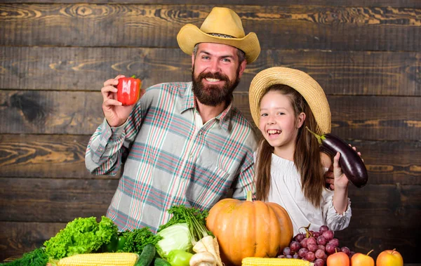 Man bearded rustic farmer with kid. Countryside family lifestyle. Family father farmer gardener with daughter near harvest vegetables. Farm market with fall harvest. Family farm festival concept