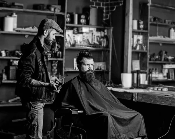 櫛とクリッパーひげを生やしたクライアントのスタイリングの髪を理容室します。流行に敏感なクライアント取得散髪。散髪のコンセプトです。床屋でバリカンは、ひげ、理髪店の背景を持つ男の髪型 — ストック写真