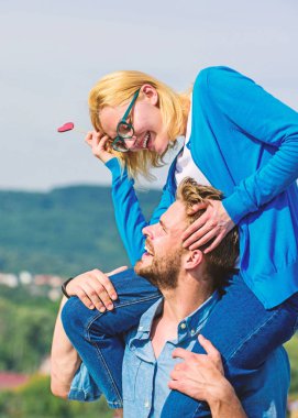 Romantik tarih kavramı. Adam kız arkadaşı omuzlarında, gökyüzü arka plan taşır. İki açık güneşli gün yürüyüş seviyorum. Çift mutlu Tarih birlikte eğleniyor. Kadın kalp aşk sopa sembolü üzerinde tutar.