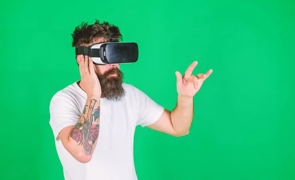 Man with long beard in VR goggles watching 3D show. Brutal bearded man enjoying recorded rock concert. Man with tattoo and stylish beard raving about 360 video of favorite band, digital era concept