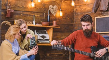 Maço acımasız yüzü elektro gitar tutuyor. Müzik aleti çalma sakallı adam. Yeni şarkı, müzik konsepti prova hipster sakallı adam. Kadın ve Genç kız müzikal performans kaydı