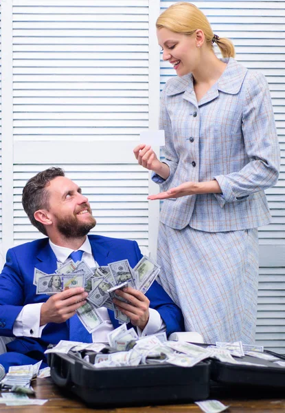 Knappe man blij en verrast met geld honderden dollars in geval. Blij en opgewonden man zit aan tafel bedekt met geld en verheugt zich met meisje secretaresse. Bank- en credit concept. — Stockfoto