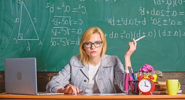 Teacher woman sit table classroom chalkboard background. Create and distribute educational content. Present lesson in comprehensive manner to facilitate learning. Promoting interactive learning — Stock Photo, Image