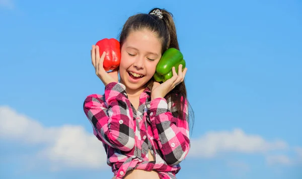 Fall harvest homegrown vegetables. Choose which. Alternative decision concept. Kid girl hold red and green peppers sky background. Kid hold ripe pepper harvest. Child presenting kinds of pepper