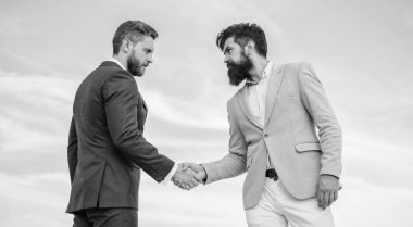 İş ortağı güveneyim işaretidir. Erkekler resmi titreyen eller mavi gökyüzü arka plan uygun. Onaylı iş anlaşması her iki ortak tarafından kabul. El sıkışırken girişimcilerin başarılı anlaşma sembolü