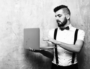 Sakallı adam dizüstü bilgisayar kullanıyor.