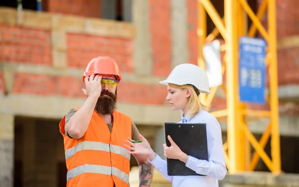 Safety inspector concept. Inspector and bearded brutal builder discuss construction progress. Construction project inspecting. Construction inspection, corrections and fines. Discuss progress project