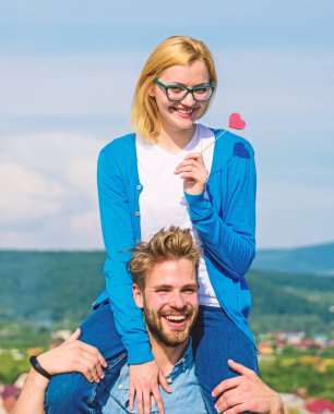 Adam kız arkadaşı omuzlarında, gökyüzü arka plan taşır. Romantik tarih kavramı. Kadın kalp aşk sopa sembolü üzerinde tutar. Çift mutlu Tarih birlikte eğleniyor. İki açık güneşli gün yürüyüş aşk içinde