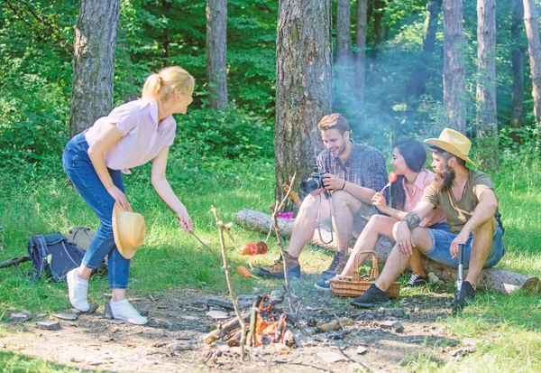 Summer picnic. Tourists hikers sit on log relaxing waiting picnic snack. Picnic with friends in forest near bonfire. Hikers relaxing during snack time. Company having hike picnic nature background