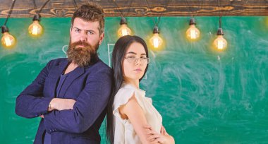 Sakal ve gözlük stand sırt sırta, kara tahta arka plan öğretmen olan adam. Öğretmen ve öğretmen rahat görünüyor. Okul personeli kavramı. Bayan ve birlikte okulda çalışan hipster