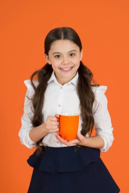 Kız çocuk okul üniforması turuncu arka plan. Kız öğrenci tutun kupa. Okul yemeği. Çay molası sırasında içme. İçkiyle rahatlatıcı. Çay molası okul. Çocuk yeterli okul gün boyunca içki yok