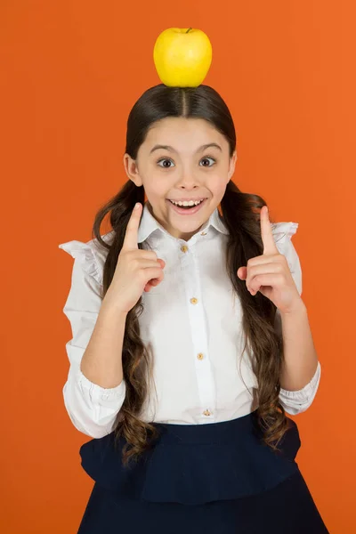 Eureka-Konzept. Verteilung von kostenlosem frischem Obst in der Schule. Mädchen Schuluniform. Schülerin mit Apfel. Schulessen. Vitaminernährung während des Schultages. Apfel auf den Kopf gefallen. Neue Idee — Stockfoto