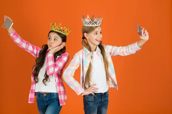 Bortskämda barn koncept. Egocentriska prinsessan. Barnen bär gyllene krona symbol prinsessan. Varningsskyltar av bortskämt barn. Undvik att höja bortskämda barn. Tjejer tar selfie foto smartphone kamera — Stockfoto
