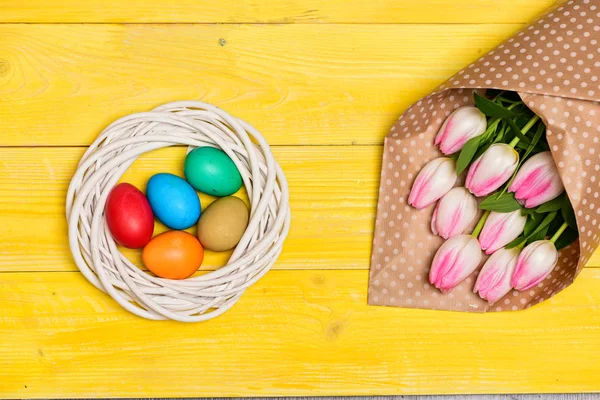 Mutlu Paskalya sezon. Paskalya yumurta sembolü. Bahar vibes. Paskalya geliyor. Renkli parlak yumurta ve buket taze Lale çiçek sarı arka plan üzerinde görünümü top. Bahar tatili. Gelenek kutlamak Paskalya — Stok fotoğraf