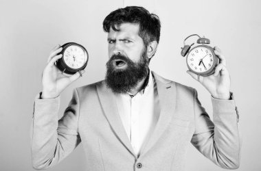 Bir adam tıraşsız şaşkın yüz zaman değişen sorunlar mı yaşıyorsunuz. Saat dilimi. Saat pislik sağlığınız ile değişen yok. Adam hipster tutun iki farklı saatler sakallı. Değişen zaman dilimleri sağlığını etkileyen