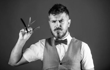 Kuaför keskin ustura ile tıraşsız hippi. Berber Kuaför Salonu. İpuçları bakım Kuaför sakal. Erkek yelek papyon ile usturanın mavi arka plan tutun. Kuaför vintage sanat kavramı