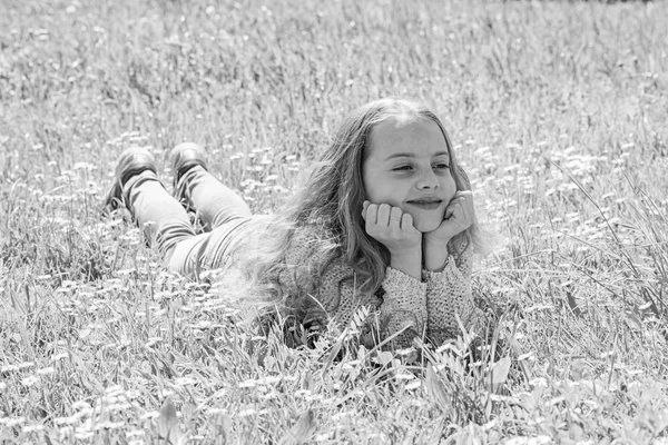 Flicka liggande på gräset på grassplot, grön bakgrund. Barn njuta av soliga vårvädret liggandes på ängen. Fred och lugn koncept. Flicka på leende ansikte tillbringar fritid utomhus — Stockfoto