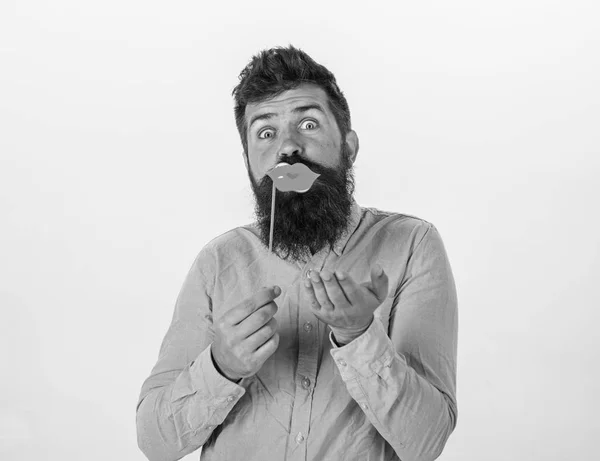 Concept amusant de photomaton. Homme tenant partie accessoires lèvres, fond blanc. Hipster avec barbe et moustache sur le visage joyeux posant avec des accessoires de photomaton, espace de copie. Le gars envoie un baiser d'air avec des lèvres rouges — Photo