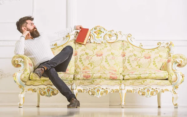 El hombre con barba y bigote pasa el ocio con el libro. Científico, profesor de cara estricta analizando literatura. Profesor sentarse en el sofá y sostiene libro, fondo blanco de la pared. Concepto de autoeducación —  Fotos de Stock