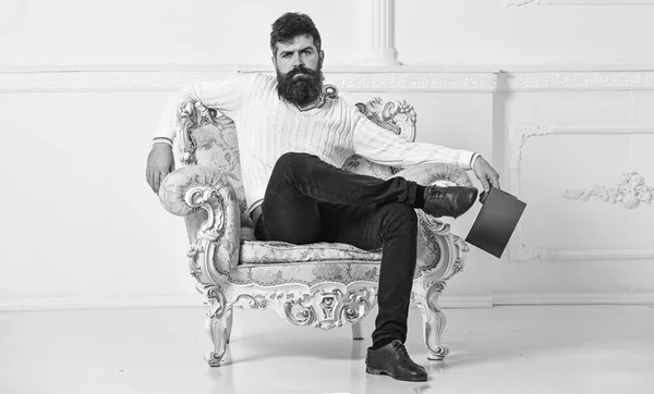 Hombre con barba y bigote se sienta en el sillón y la lectura, fondo blanco de la pared. Conocedor, el profesor disfruta de la literatura. Conocedor del concepto de literatura. Macho pasa el ocio con el libro —  Fotos de Stock