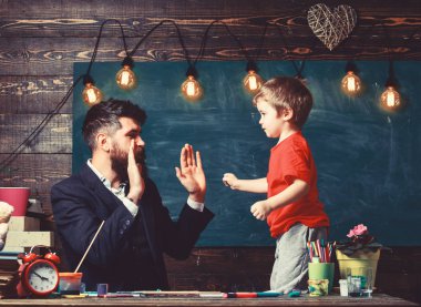 Sanat ders kavramı. Çocuk neşeli ve öğretmen çizim sırasında eğlenin. Yetenekli sanatçı oğlu ile vakit geçirmek. Öğretmen sakallı, baba oğul sınıfta, kara tahta arka plan çizmek için öğretir.