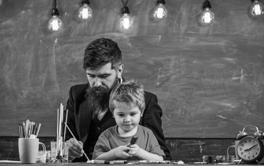 Öğretmen sakal, baba ve küçük oğul çizerken, sınıfta oluşturma, kara tahta arka plan ile. Çocuk ve resim, çizim meşgul yüzleri öğretmen. Çizim ders kavramı