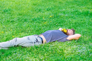 Sakal karahindiba çiçeklerle sakallı adam çayır, çimen arka plan üzerinde yatıyordu. Hippi sakal rahatlatıcı dandelions buket. Sakallı yüzü uyku üzerinde bahar tadını çıkarın. Bahar kavramı