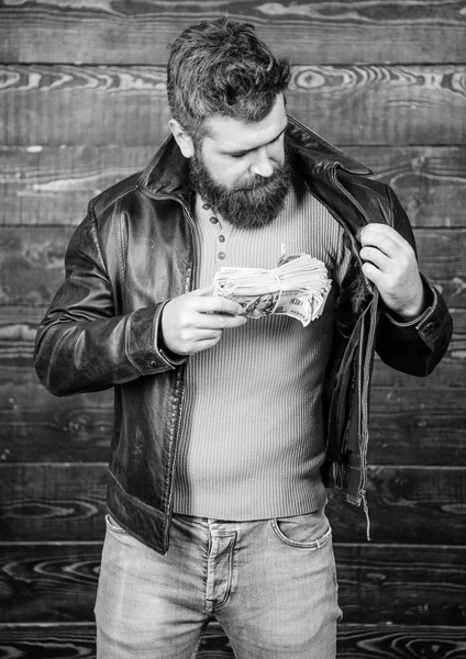 Mafia business. Illegal profit and black cash. Guy mafia dealer with cash profit. Brutal man has cash money. Richness and wellbeing. Man brutal bearded hipster wear leather jacket and hold cash money