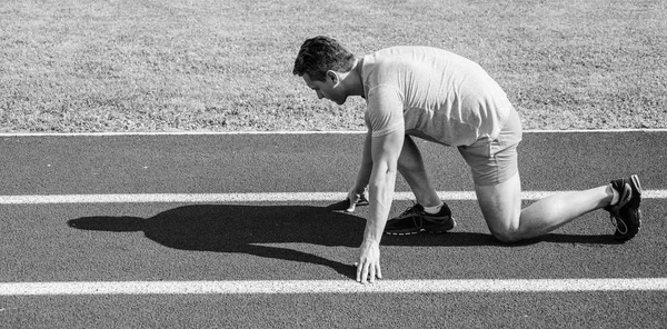 Esfuérzate por ganar. Corredor adulto preparar carrera en el estadio. Cómo empezar a correr. Concepto de motivación deportiva. Hombre atleta corredor de pie baja posición de inicio camino del estadio día soleado. Corredor listo para salir — Foto de Stock