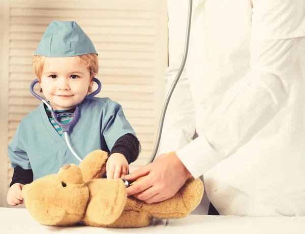 Gezondheid en kindertijd concept. Kleine assistente onderzoekt teddybeer. — Stockfoto