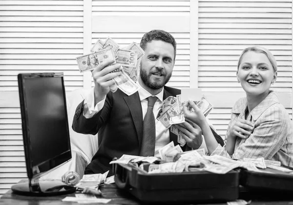 Bonito homem feliz e surpreso com dinheiro centenas de dólares no caso. Jovem empresário olhando para o dinheiro espalhado na mesa. Conceito de lucro e riqueza . — Fotografia de Stock