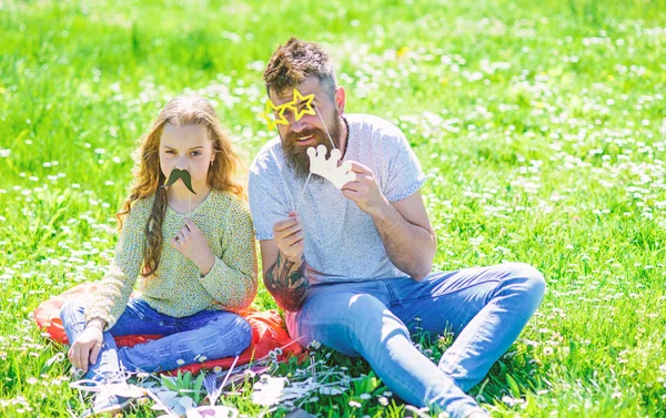 Baba ve kızı, grassplot, arka planı yeşil çimenlerin üzerinde oturur. Çocuk ve babası eyeglases ve bıyıklı photo booth öznitelikleri ile poz. Aile açık havada eğlence harcamak. Aile zaman kavramı — Stok fotoğraf