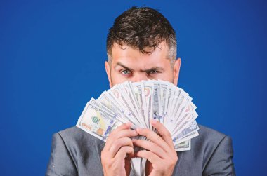 İşadamı nakit para var. Zenginlik ve refah kavramı. Nakit para kolay ve hızlı bir şekilde almak. Para gibi kokuyor. Resmi takım elbise mavi arka plan doları banknot yığını tutun. Kolay nakit krediler