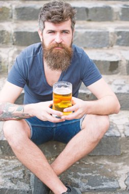 Uzun sakallı hippi rahat görünüyor. Sakallı hippi bira bardağı tutan, açık bira içiyor. Sakal ve bıyık sakin yüz, taşlı arka plan, defocused olan adam. Zanaat bira kavramı