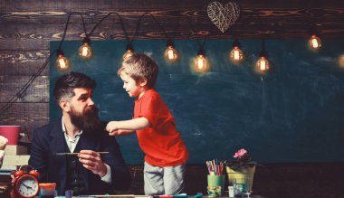 Sanat ders kavramı. Çocuk ve meşgul yüz boyama, resim öğretmeni. Yetenekli sanatçı oğlu ile vakit geçirmek. Sakallı öğretmen, babası sınıfta, kara tahta arka plan çizmek için küçük oğlu öğretir.