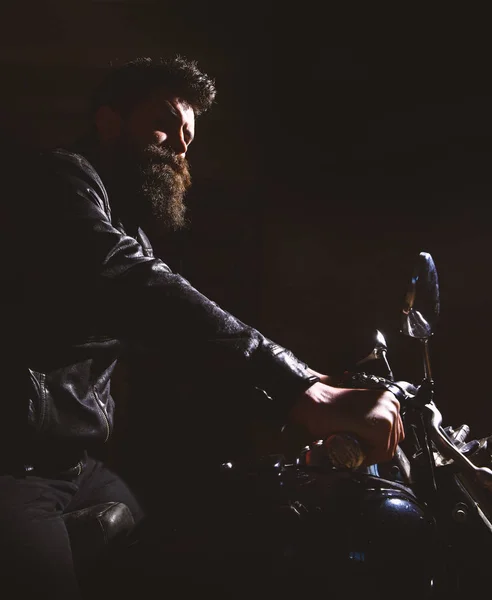 Hipster, motociclista brutal em jaqueta de couro andar de moto à noite, espaço de cópia. Homem com barba, motociclista de jaqueta de couro sentado em moto no escuro, fundo preto. Conceito de cavaleiro nocturno — Fotografia de Stock