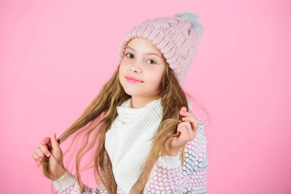 Criança cabelo comprido sorrindo. Menina usar chapéu de malha fundo rosa. Evite danos no cabelo no inverno. Dicas de cuidados com o cabelo de inverno que você definitivamente deve seguir. Inverno treinar-se para ir mais tempo entre lavagens — Fotografia de Stock