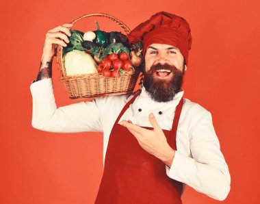 Kırmızı zemin üzerine sakallı adam. Şef sebze tutar