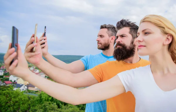 Selfie traído por la confianza en sí mismo. Mujer bonita y hombres sosteniendo teléfonos inteligentes en las manos. Mejores amigos tomando selfie con el teléfono de la cámara. Gente disparando selfie en la naturaleza. Compartir selfie en las redes sociales — Foto de Stock