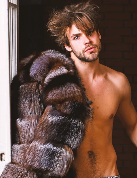 Sexy macho peluqueado saliendo por la puerta del dormitorio. Riqueza y concepto de lujo. Amante rico soltero. Chico atractivo posando abrigo de piel en cuerpo desnudo. Estilo de vida y bienestar de lujo. Símbolo de lujo — Foto de Stock