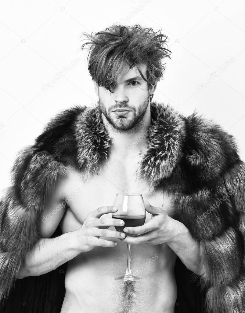 Sexy sleepy rich macho tousled hair drink wine isolated on white. Health and wellbeing. Richness and luxury concept. Guy attractive rich posing fur coat on naked body. Rich athlete enjoy his life