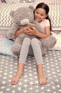 İleti tatlı rüyalar gönderin. Kız çocuk yatak yatak odasında oyuncak ayı ile oturmak. Çocuk yatmaya hazırlanın. Kız çocuk uzun saçlı şirin pijama peluş oyuncak ayı oyuncak rahatla. Çocuk akıllı telefon mesaj gönder