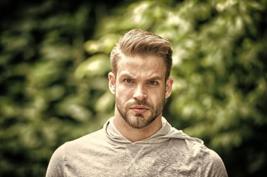 Yakışıklı tarzı. Adam görünümü hakkında çekici umurunda sakallı. Adam defocused ciddi bir yüz, yeşil doğa arka plan, kıl. Metroseksüel kavramı. Adam sakal tıraşsız adam yakışıklı ve serin görünüyor