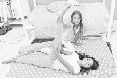 Kız çocuğu yatak odasında bölünmüş olarak oturur. Arkadaş jimnastikçileri birbirlerini desteklerler. Spor yaşam tarzı. Kız çocuk pijamaları esniyor. Esneme egzersizi. Günlük rejimi genişletiyorum. Jimnastikçi arkadaşından ayrıldı.