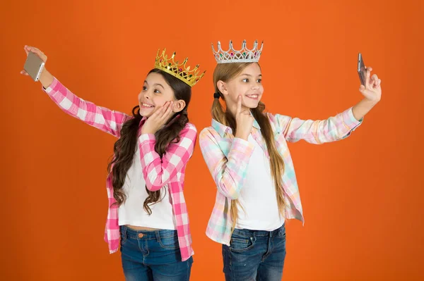 Princesa egocéntrica. Los niños usan coronas doradas símbolo princesa. Señales de advertencia de un niño malcriado. Evita criar niños malcriados. Chicas tomando foto selfie cámara del teléfono inteligente. Concepto de niños mimados —  Fotos de Stock