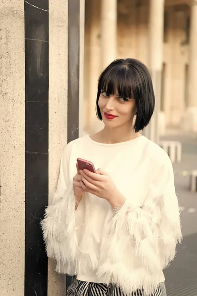 Mulher com cabelo morena segurar telefone celular. Mulher com lábios vermelhos usar smartphone em Paris, França. Menina de beleza com olhar sexy. Modelo de moda com dispositivo móvel. Nova tecnologia para a vida moderna — Fotografia de Stock