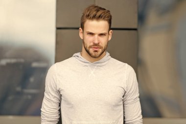 Metroseksüel kavramı. Adam sakallı ve çekici görünümü ile ilgili umurunda değil. Ciddi yüz, kentsel arka plan, defocused kıl olan adam. Adam sakal veya tıraşsız adam yakışıklı ve serin görünüyor