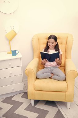 Okuma onun hobisiydi. Kız çocuk sit sarı koltuk kitabını okudum. Çocuk yatmaya hazırlanın. Keyifli zaman rahat yatak odasında. Kız çocuk uzun saçlı şirin pijama rahatla ve uyku önce masal kitabı okuyun